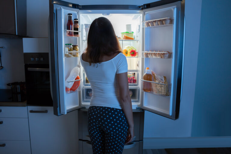 Young woman standing at an open fridge